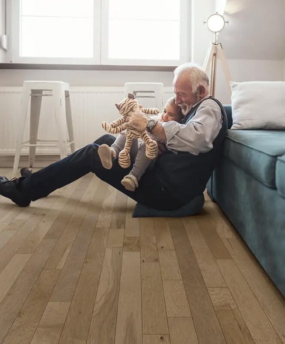 Grandfather and grandchild playing on a hardwood floor in a family home
